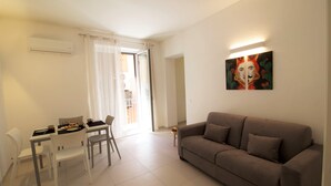 Una sala de estar con un sofá, una mesa de comedor con sillas y un cuadro en la pared.