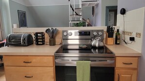 A kitchen with a built-in oven, a microwave, and a toaster. There is a green towel hanging on the oven door.