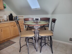 Cozy dining area with a round table and four chairs, featuring a coffee maker and kettle.