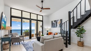 A spacious living area with a large window, a ceiling fan, a staircase, and a view of the ocean. - GOOD VISIBILITY ~ 4 Bedroom, 3 Bathroom Condo w/ Pool and Ocean Views! (Key West)