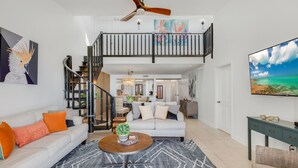 A spacious living room with a white sofa, a coffee table, and a staircase leading to an upper level. - GOOD VISIBILITY ~ 4 Bedroom, 3 Bathroom Condo w/ Pool and Ocean Views! (Key West)