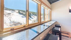 A room with large windows offering a view of a snowy landscape and a ski lift.