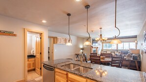 A kitchen with granite countertops, wooden cabinets, and pendant lighting.