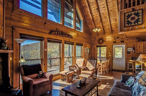 A cozy cabin interior with a wooden interior, large windows, and a dining area.