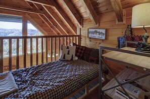 Een houten kamer met een bed, een tafel en uitzicht op het bos.