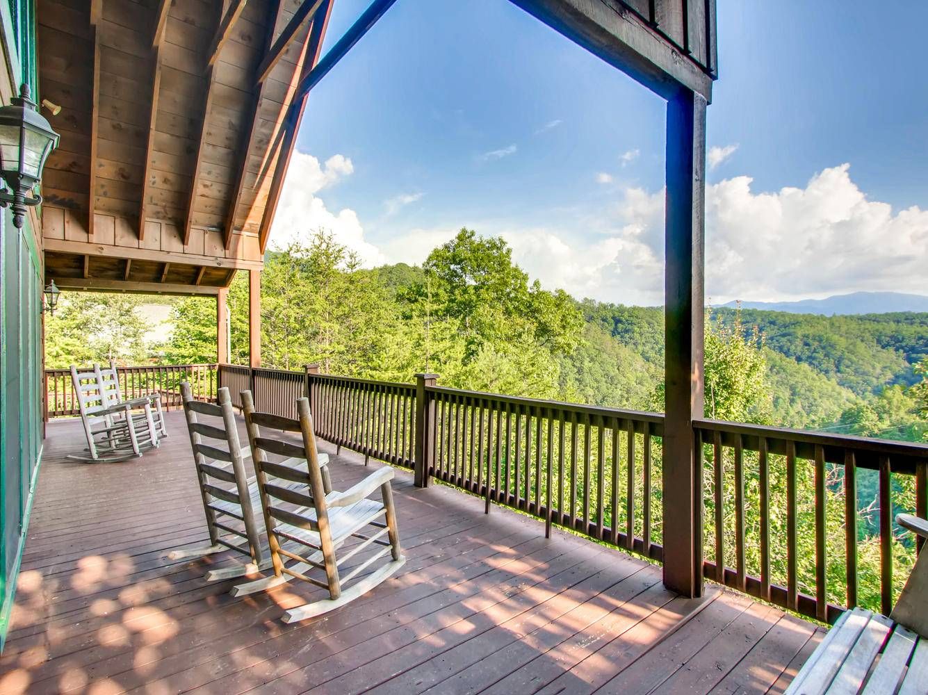 A wooden deck with a railing overlooking a forested valley.