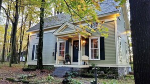 Een woonhuis met twee verdiepingen, een veranda, stenen treden en een stenen muur rondom het terrein.