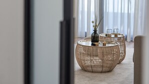 Uma sala de estar moderna com uma janela grande, um sofá e duas mesas de centro redondas.