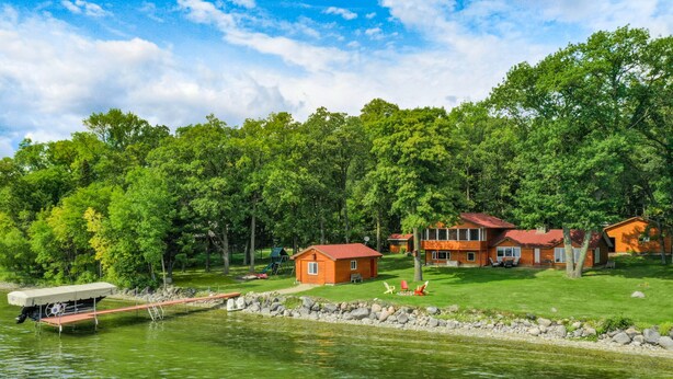 Un ensemble de chalets situés au bord d’un lac, comprenant plusieurs chalets, un quai et une pelouse.