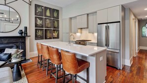 A modern kitchen with a central island, stainless steel appliances, and a dining area with leather chairs.