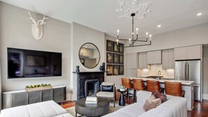 A modern living room with a fireplace, a flat-screen TV, and a dining area with bar stools.