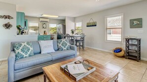 Een ruime woonkamer met een blauwe bank, een houten salontafel en een plafondventilator.