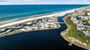Luftaufnahme einer Küstenregion mit Strand, einem Yachthafen und Wohngebäuden.
