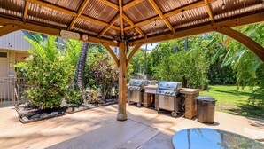 Un patio al aire libre con una zona de estar techada, una parrilla y una mesa de billar.