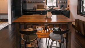 Een moderne keuken met een houten tafel en barstoelen, voorzien van een koelkast, fornuis en diverse keukengerei.