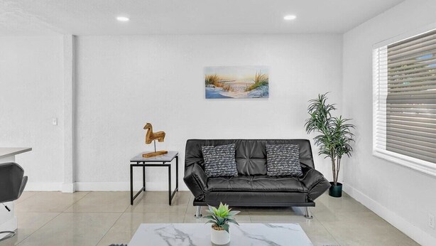 Ein modernes Wohnzimmer mit einer schwarzen Ledersofa, einem kleinen Holztisch, einem Gemälde an der Wand und einer Zimmerpflanze.