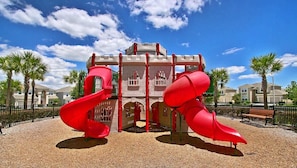 A playground with two red slides and a castle-like structure.