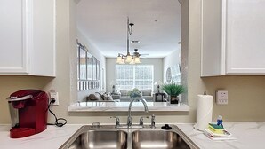 A kitchen with a double sink, a red coffee maker, and a mirror reflecting the living room. - New! Windsor Hills Galaxy's Edge Home, 2mi to Disney!! (Kissimmee)