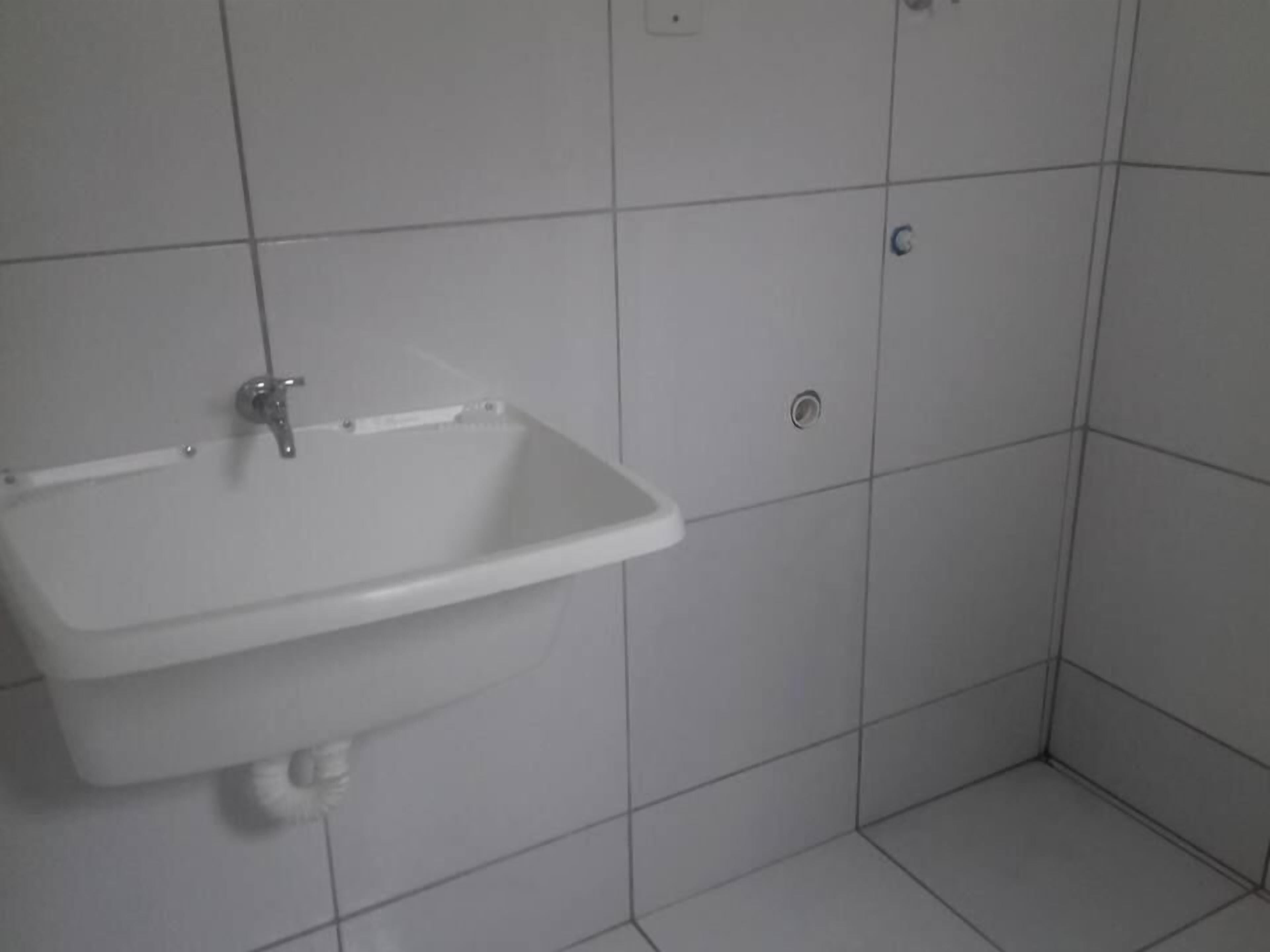 Une salle de bain avec un lavabo blanc, un miroir et un sol carrelé.
