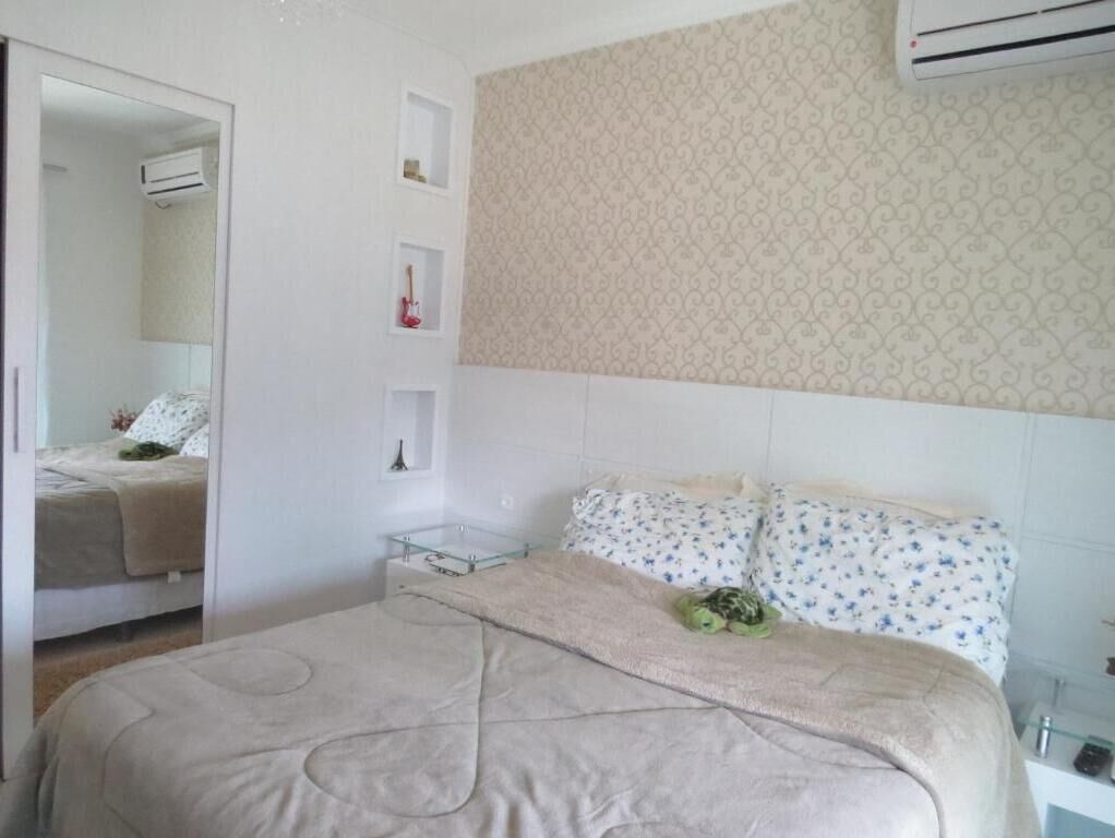 A bedroom with a bed, a mirror, a wardrobe, and an air conditioning unit.