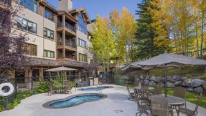 A pool area with two hot tubs, outdoor seating, and a building with balconies. - Ski-In & Out Your Doorstep! Lovely Interior, Pool/Hot Tub! (Beaver Creek)