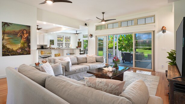 A spacious living room with a large sectional sofa, a coffee table, and ceiling fans.