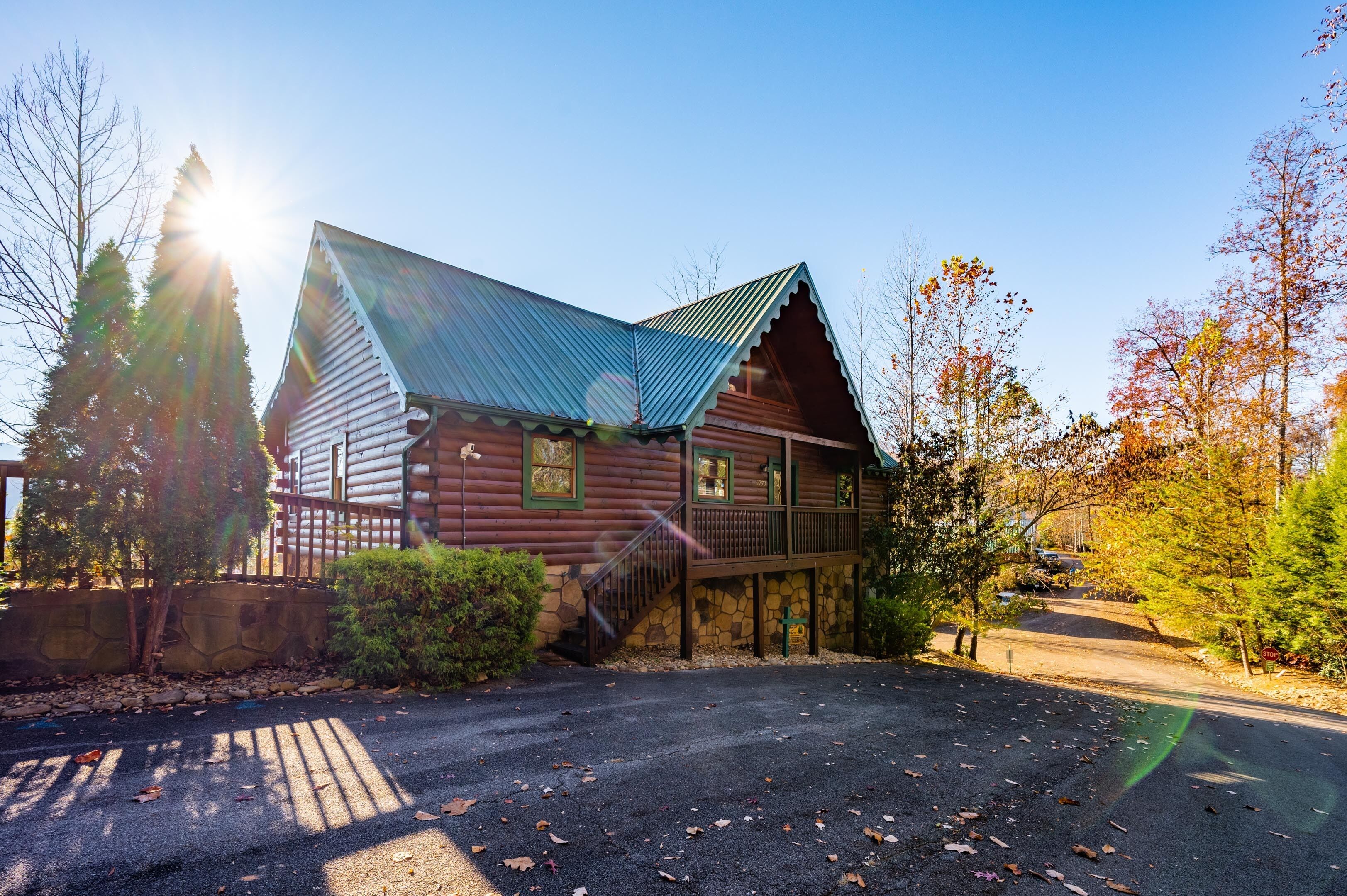 A log cabin with a metal roof, a stone foundation, and a wooden deck.