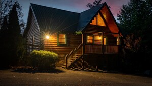 A log cabin with a porch, a staircase, and a lit window. - Epic Views, Perfect Location, Fast WiFi (Gatlinburg)