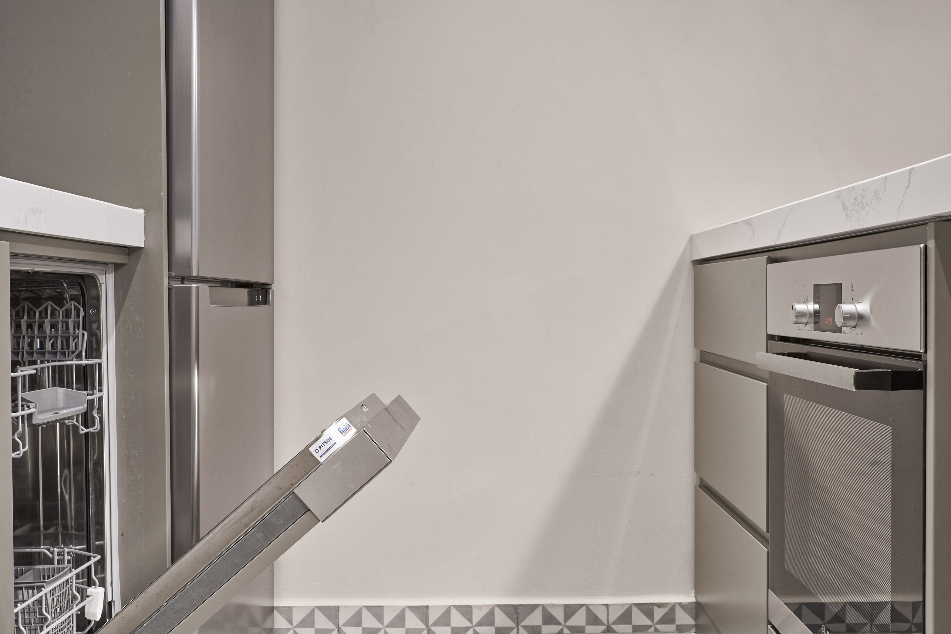 Et køkken med rustfrie hårde hvidevarer, en opvaskemaskine og et flisebeklædt backsplash.
