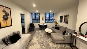 A living room with a grey sofa, a black and white patterned rug, and a dining area with a small round table and chairs. - Large 2 bdrm Flinders St apt on Hosier Lane, with AC. Easy walk to MCG/Aust Open (Melbourne)