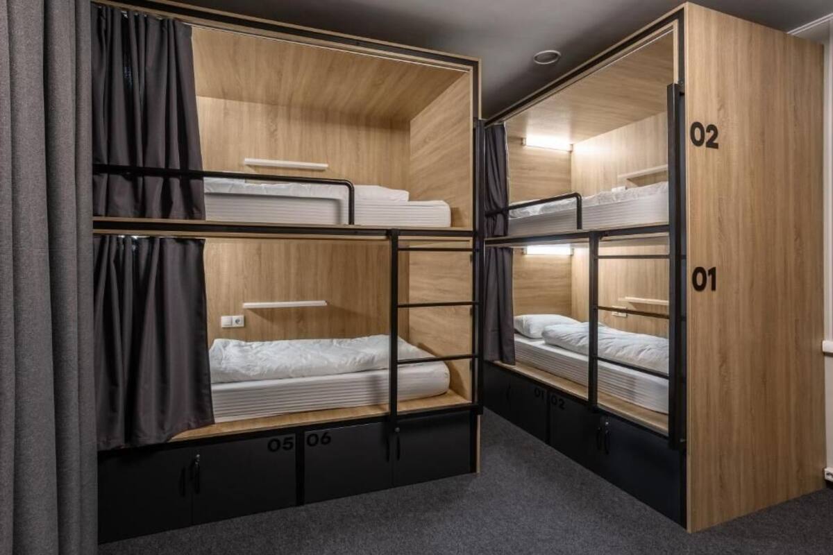 A bunk bed room with wooden walls and black metal frames. There are curtains on the left side.