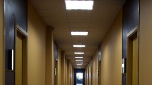 A long, narrow hallway with doors on both sides, a blue carpet, and fluorescent ceiling lights. - Kiev Hostel (Kyiv)