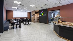 A modern hostel interior with a herringbone floor pattern, a buffet area, and a seating area with tables and chairs. - Kiev Hostel (Kyiv)