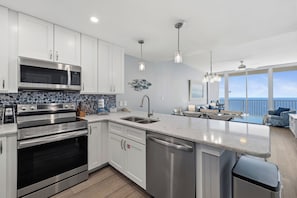A modern kitchen with stainless steel appliances, a dishwasher, and a large island.