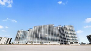 Een groot, meerlaags hotel met een modern ontwerp, met veel balkons en een plat dak.