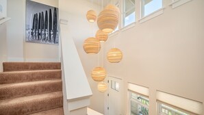 A staircase with patterned carpet, a white door, and hanging spherical lamps. - Pili Mai Family Condo 6G, 2 Bedroom, 2 Bath, Plus Loft with Queen Murphy Bed (Koloa)