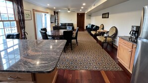 A modern kitchen with a marble countertop, a dining area with a round table, and a living area with a sofa and chairs. - 3BR/3BA + 3 Parking — Harvard/MIT, Red & Green Lines (Cambridge)