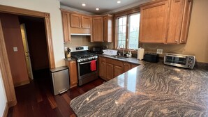 A kitchen with wooden cabinets, a granite countertop, a stainless steel stove, a refrigerator, and a toaster. - 3BR/3BA + 3 Parking — Harvard/MIT, Red & Green Lines (Cambridge)
