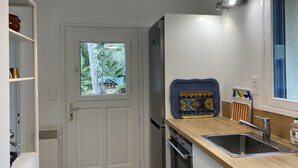 Eine moderne Küche mit Einbauofen, Edelstahlspüle und einem Fenster mit Blick auf Bäume.