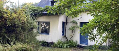 Une maison rustique avec un toit en pente, une petite fenêtre et une porte.