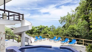 Ein Poolbereich mit blauen Fliesen, einer Wendeltreppe und blauen Liegestühlen.