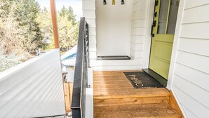A wooden staircase leading to a green door, with a white railing and a small shelf above. - Midtown gem I Park view I Full kitchen (Bend)