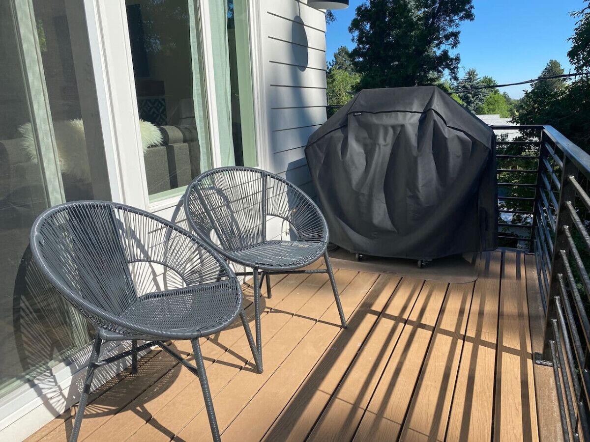 Eine Holzterrasse mit zwei Stühlen und einem überdachten Grill.
