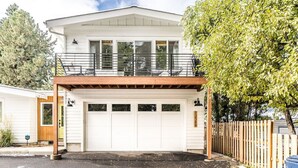 A two-story house with a garage, a balcony, and a wooden deck. - Midtown gem I Park view I Full kitchen (Bend)
