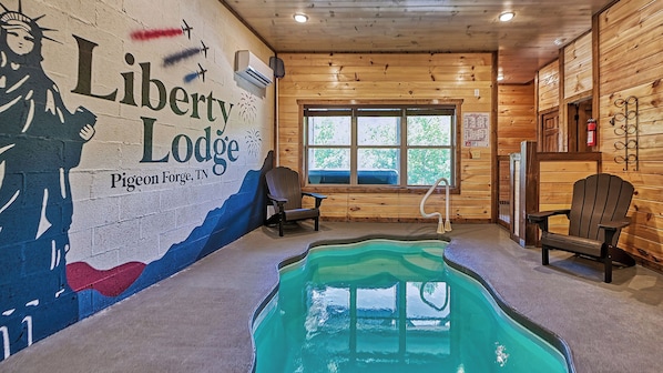 A cabin interior with a pool, Adirondack chairs, and a mural of a person holding a torch.