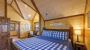 A wooden cabin room with a bed, a bench, a window, and a sign that says 'blessed'.