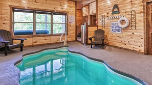 L’intérieur d’un chalet en bois comprend une piscine, deux fauteuils Adirondack, une fenêtre et un panneau indiquant qu’il est interdit de plonger.