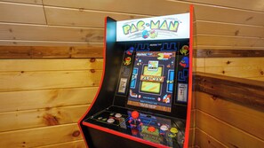 A Pac-Man arcade machine with a start game button, joystick, and score display.