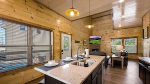 A cabin interior with a kitchen, dining area, and a fireplace.