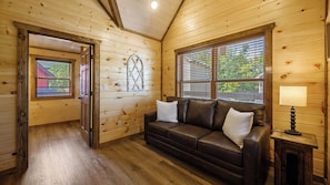 Ein Holzblockbau-Innenraum mit Ledersofa, Lampe und Fenster mit Rollläden.
